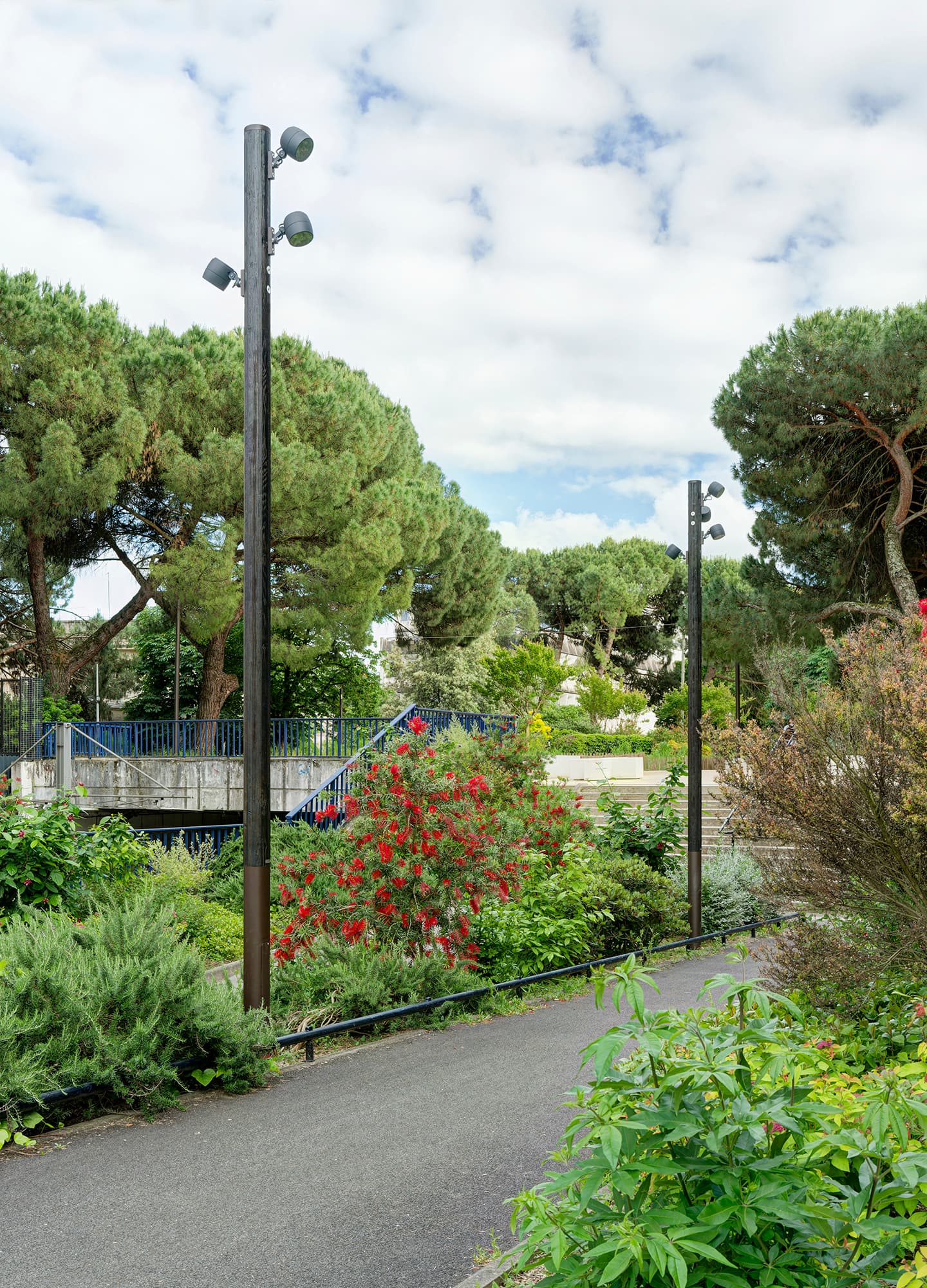 Mâts d'éclairage en bois Aubrilam installés le long d'un cheminement arboré